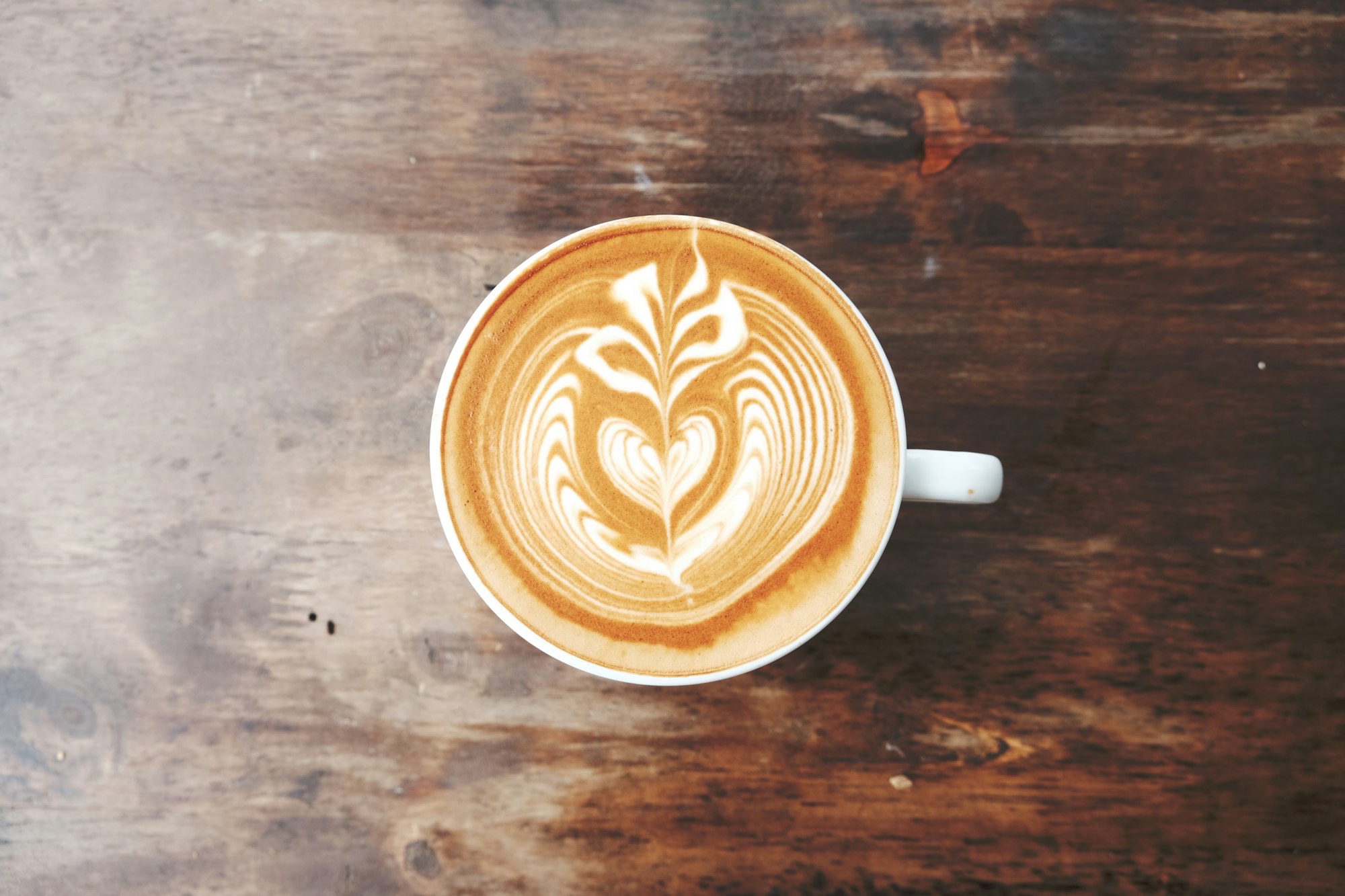Vista dall'alto di un cappuccino con decorazione in latte art su un tavolo di legno